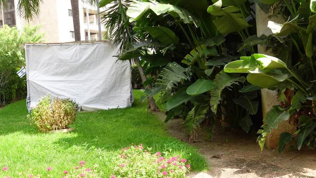 Jewish festival of Sukkot in Israel. Traditional sukkah with handmade decorations near the building on the street. 