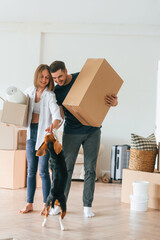 Holding boxes. Young couple moving to new home