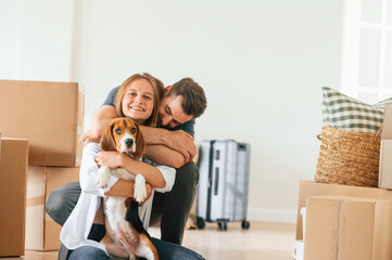 Embracing each other. Young couple with dog are moving to new home