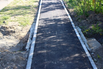 Paved asphalt pedestrian path, narrow sidewalk on the street