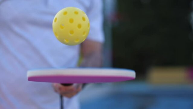 Pickleball player juggling with a ball in slow motion