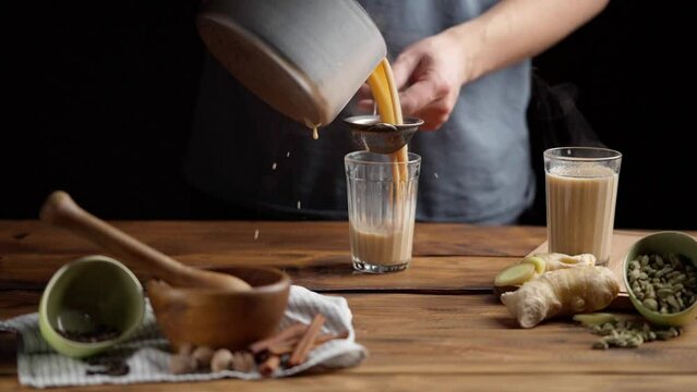 A man pours masala tea into a cut glass.