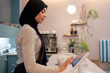 Young woman in hijab working in cafe - obrazy, fototapety, plakaty