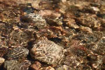 Shallow stream of water surrounded by small rocks in an area with no foliage