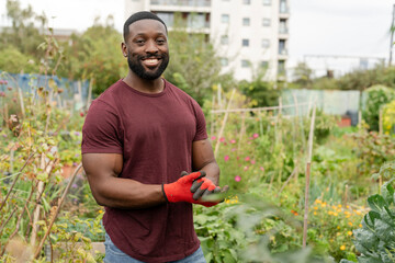 Portrait of smiling man standing in urban vegetable garden