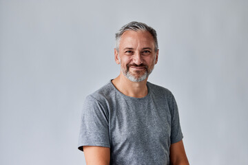 A happy senior male posing on the white background, dressed casually. Grey bearded and haired man.