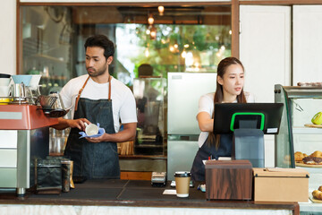 cafe owner multiracial male business couple cleaning coffee cups coffee maker Asian girlfriend checking orders store closed credit card swipe machine paper coffee cups attentively cafe small business. - obrazy, fototapety, plakaty