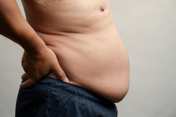 Naklejka premium Profile view of man with pot belly against gray background