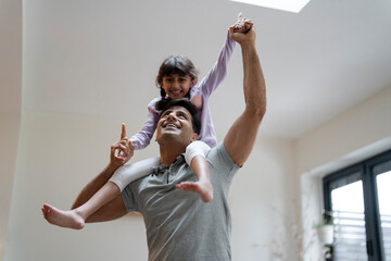 Father carrying daughter on shoulders at home