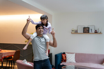 Father carrying daughter on shoulders at home