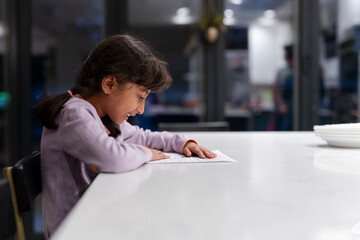 Little girl reading at table