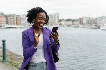 Smiling woman using smart phone by river