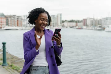 Poster Smiling woman using smart phone by river © Cultura Creative
