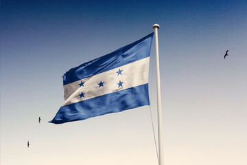 Fototapeta premium Honduras flag fluttering in the wind on sky.