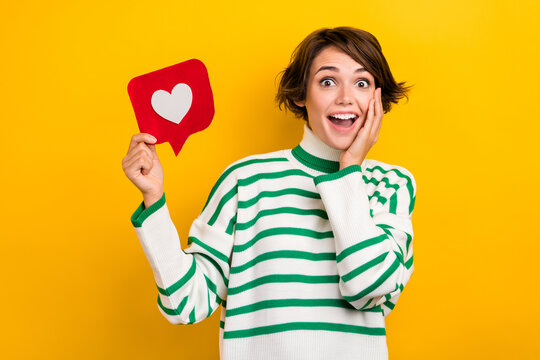 Photo of sweet shocked lady wear striped pullover arm hand cheek cheekbone rising heart like card isolated yellow color background