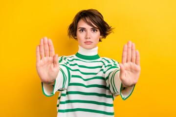 Photo of serious confident girl dressed striped sweater showing arms stop isolated yellow color...