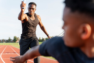 Two athletes running in relay race - obrazy, fototapety, plakaty