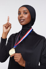 Studio portrait of young woman in hijab wearing gold medal © Cultura Creative