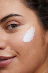 Close-up of young woman applying face cream