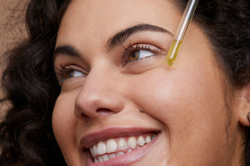 Close-up of young woman applying face serum