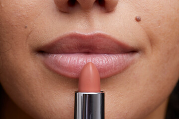 Close-up of young woman applying lipstick