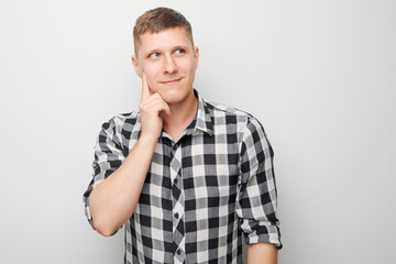 Portrait of clever man in shirt touching chin thinks doubts chooses isolated on white studio background with copy space