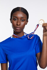 Studio portrait of athletic woman with golden medal © Cultura Creative