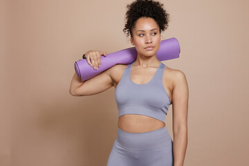 Studio portrait of athletic woman with yoga mat