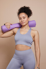 Studio portrait of athletic woman with yoga mat