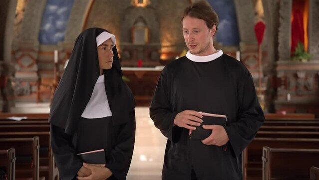 Man and Woman Talking in Church about Religion and Faith. Nun and Priest Walk Inside Church before Prayer. Young Adult Pope and Sister Talk about God Together Indoor Chapel. Talk about Bible and Jesus