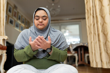 Portrait of Muslim woman with down syndrome praying at home
