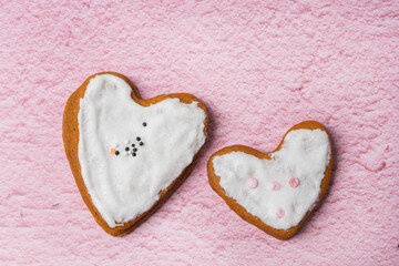 Obraz premium Two gingerbread cookies with white icing are on a pink background