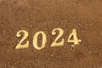 Happy New Year concept. Gold text 2024 number on floor soil surfaces