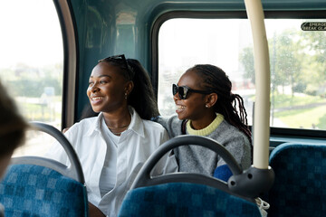 Young female friends riding city bus - obrazy, fototapety, plakaty