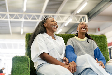 Young female couple relaxing on sofa in shopping center © Cultura Creative