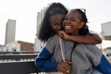 Portrait of young stylish female couple hugging in city
