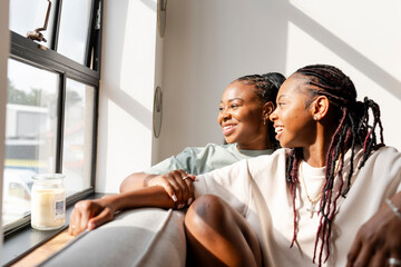 Portrait of happy lesbian couple looking through window at home