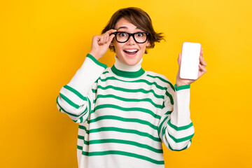 Photo of excited pretty lady wear striped pullover spectacles showing modern gadget display empty space isolated yellow color background