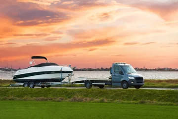 Deurstickers Luxury Boat Journey on the Road at Sunset. Modern motorboat delivery on the driveway. Sunset sky. © AlexGo