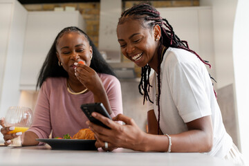 Lesbian couple using phone during breakfast in kitchen