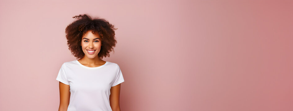 afro woman with curly hair, with a positive expression, wearing a casual white t-shirt, pink background