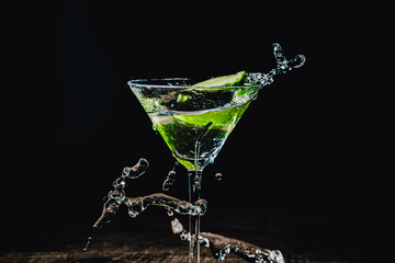splash in a glass with lime slice on a black background