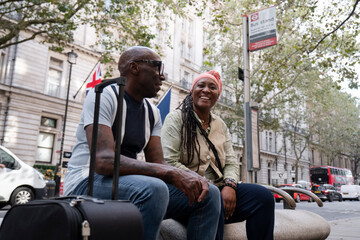 Fototapeta na wymiar UK, London, Happy mature couple sitting at bus stop