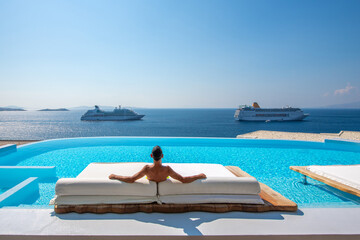 Man relaxes on the sunbed at Mykonos, Greece - obrazy, fototapety, plakaty