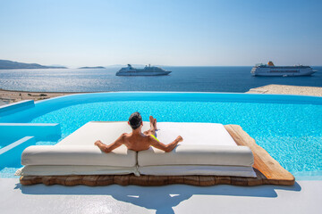 Man relaxes on the sunbed at Mykonos, Greece - obrazy, fototapety, plakaty