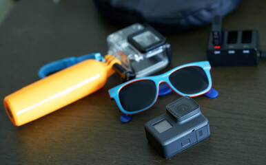 action camera and sun glasses on table for travel concept