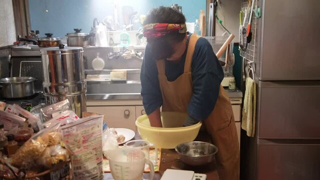自宅でそばを打つ女性