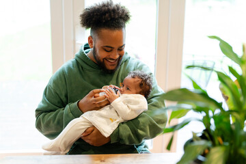 Father feeding baby daughter at home