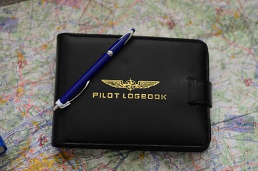 Top view of a pilot's logbook with a pen on the map on the table