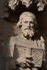 Fototapeta premium Closeup of intricately carved stone statue mounted above a brick wall in Lichfield Cathedral, UK